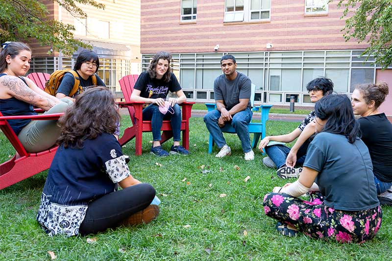 Eight researchers in the SEALab sit in chairs and on the grass in a courtyard on Northeastern's Boston campus
