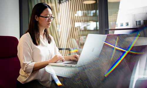 Tianshi Li types on a laptop while sitting at a table