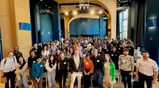 Over 200 NEMI attendees pose for a photo in a large auditorium