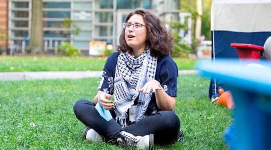 Leah Rosenbloom speaks while sitting on grass in a courtyard