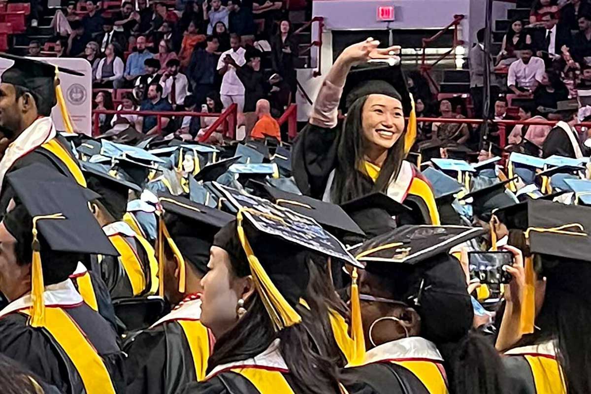 A graduate waves to the crowd during the ceremony