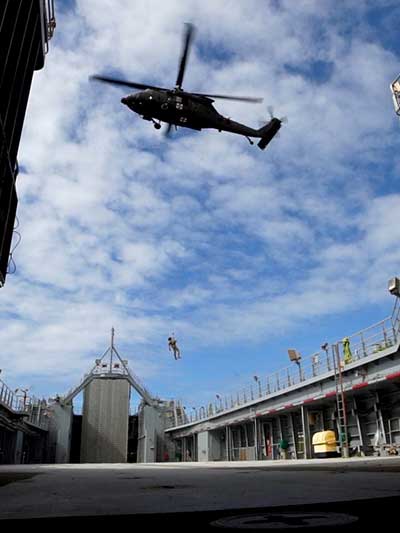 A person dangles from a rope attached to a helicopter above