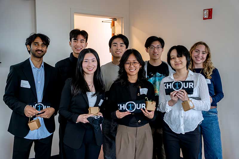 Eight students who benefitted from the F1RST fund hold up gift bags at an event
