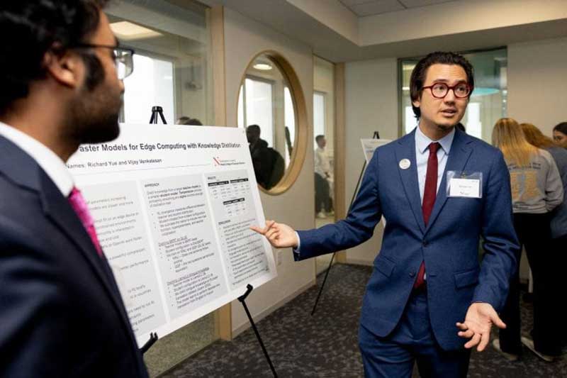 A Khoury Silicon Valley talks to a group while standing next to his research poster