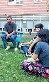 Three researchers in the SEALab sit in chairs and on the grass in a courtyard on Northeastern's Boston campus