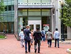 Groups of students walk to the doors of West Village H. A Khoury College sign is visible above the door.
