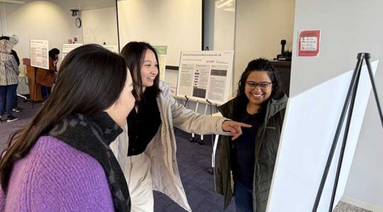 Three students read a project poster