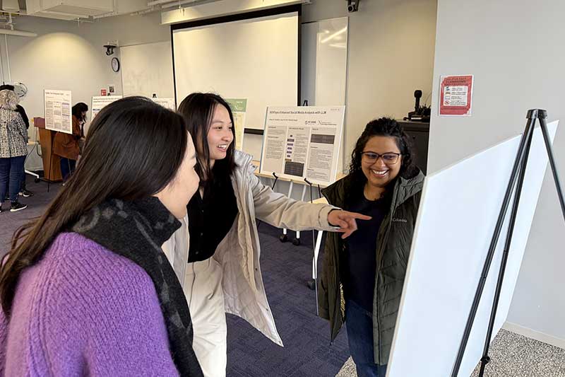 Three students read a project poster