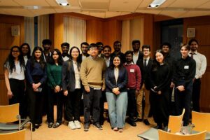 Twenty Khoury master's students pose for a photo before the research showcase