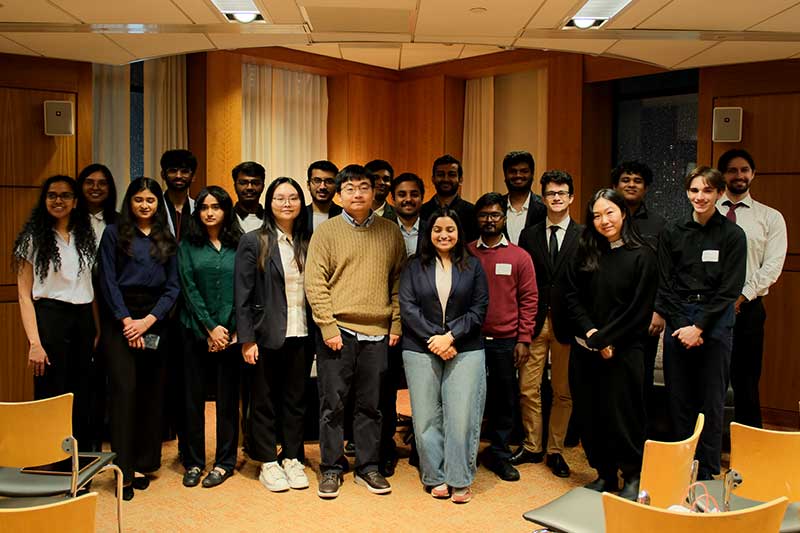 Twenty Khoury master's students pose for a photo before the research showcase