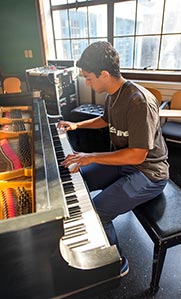 A Khoury student plays a grand piano