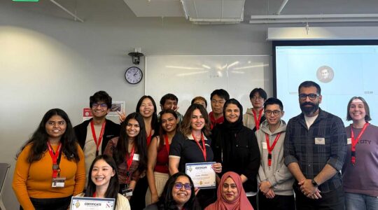 17 members of the Innovation Consulting Club hold award certificates and pose for a photo in a classroom