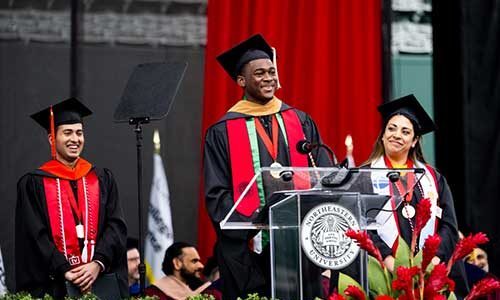 Graduate students Abou-Bakar Mohamed Ouattara, Menahi Shayan and Daniela Gonzalez stand on the stage at commencement