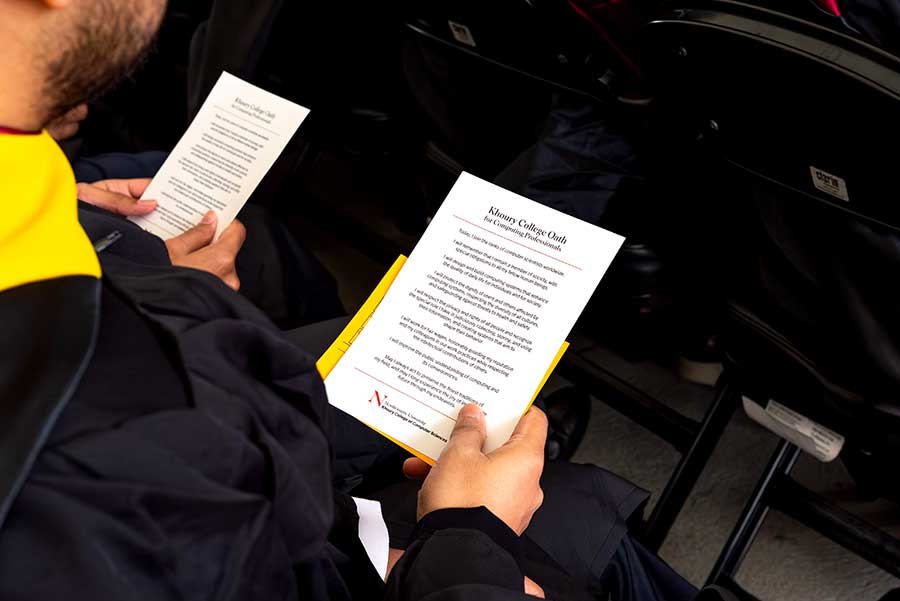 Two students hold cards containing the Khoury College Oath for Computing Professionals