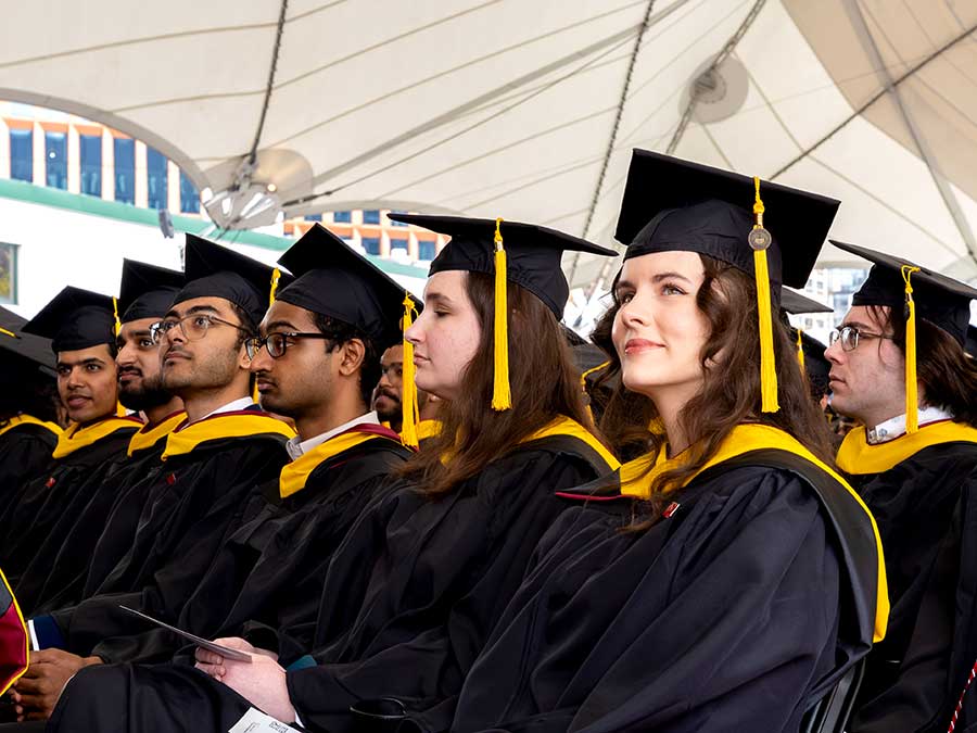 A row of graduating master's students look forward toward the stage at the master's student commencement ceremony