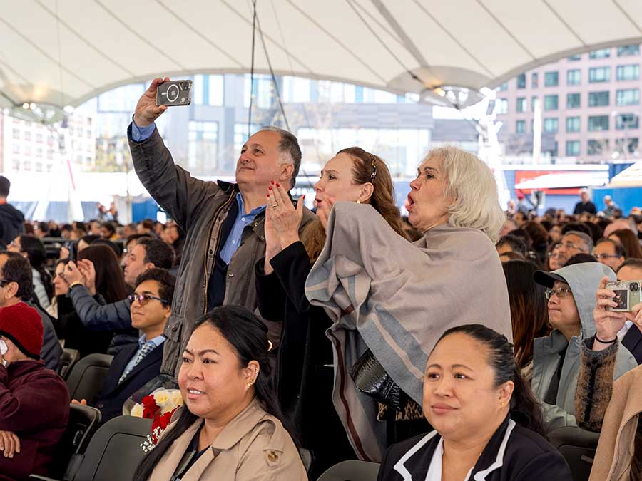 Family members of Khoury graduates stand up and take pictures and cheer for graduates