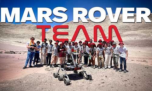 Several members of the NU Mars Rover Team stands behind their robotic rover