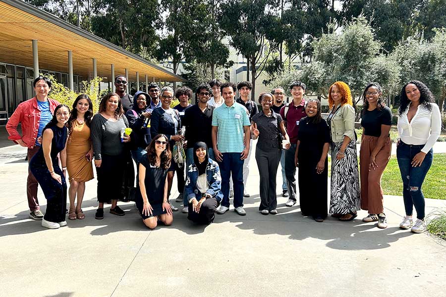 Several Khoury students and about 12 local business leaders pose for a photo in a courtyard