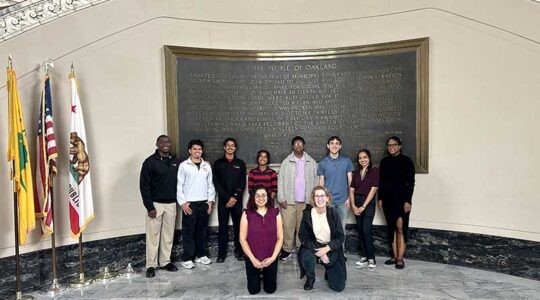 Khoury faculty and students smile in front of a large plaque in Oakland City Hall