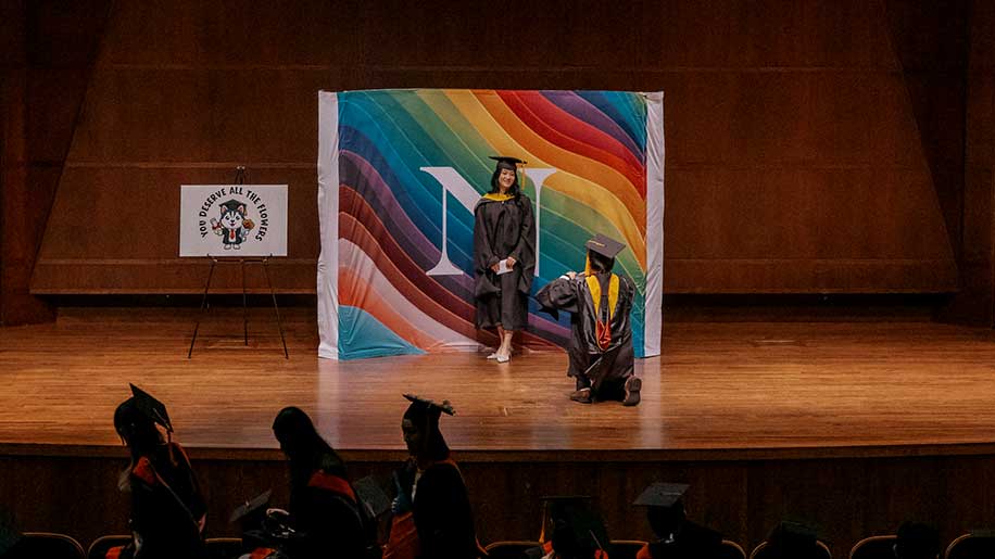 Khoury graduate Dong Cheng poses against a colorful background during the ceremony
