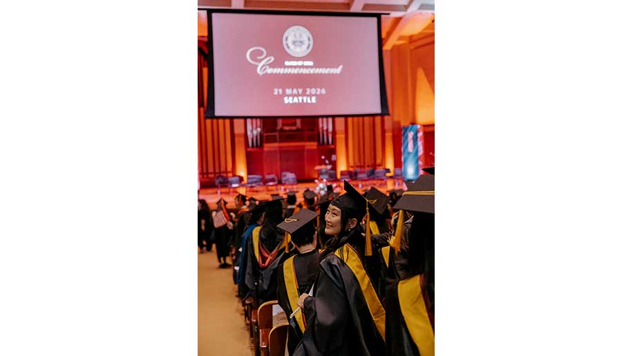 A graduate seated on the end of a row looks back at the graduation audience