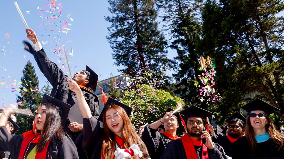 Five Khoury graduates celebrate as confetti is shot in the air behind them