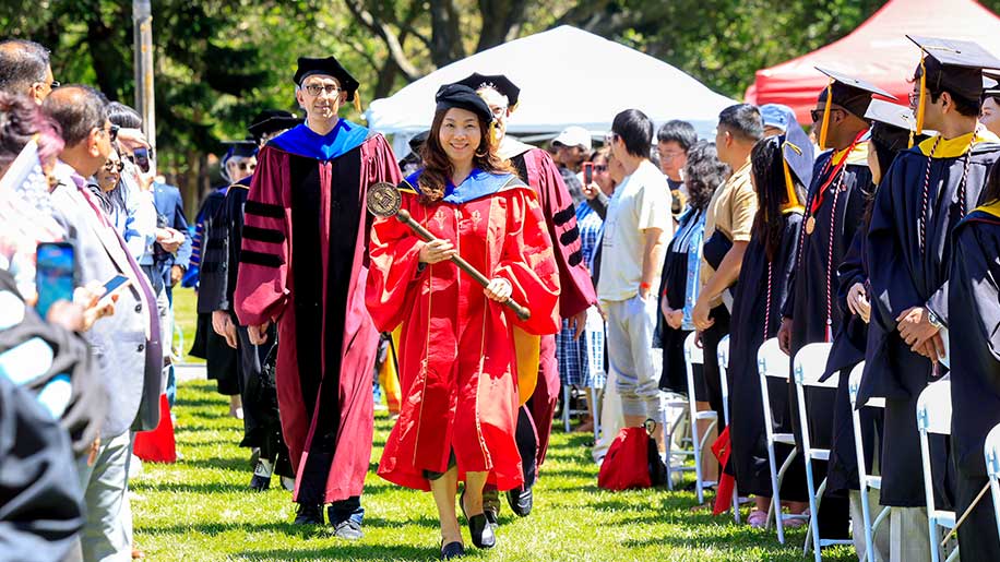 Ilmi Yoon, director of computing programs for Silicon Valley, leads the procession of faculty between two sections of audience seating