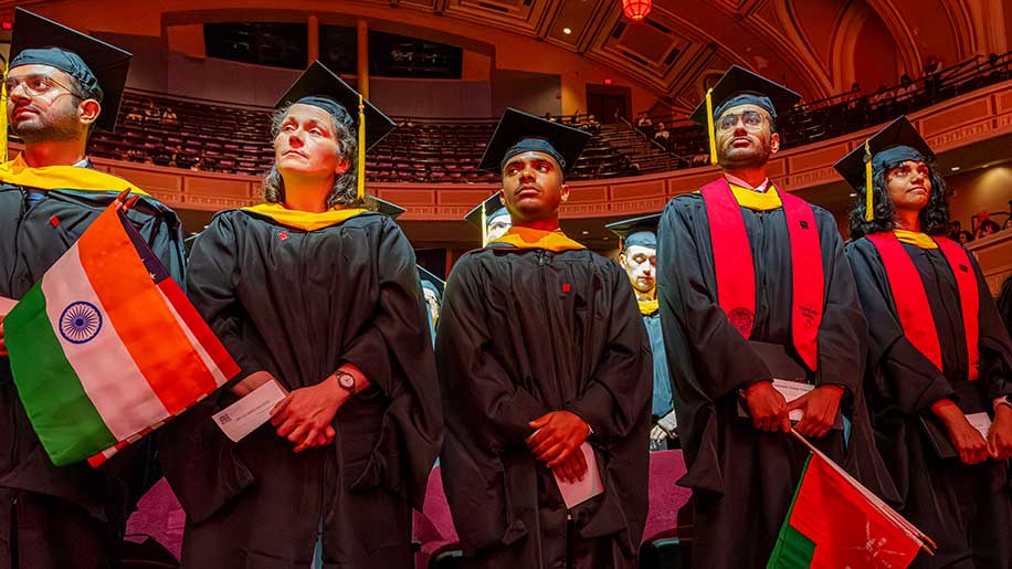 Graduates hold flags of different nations, including India and China