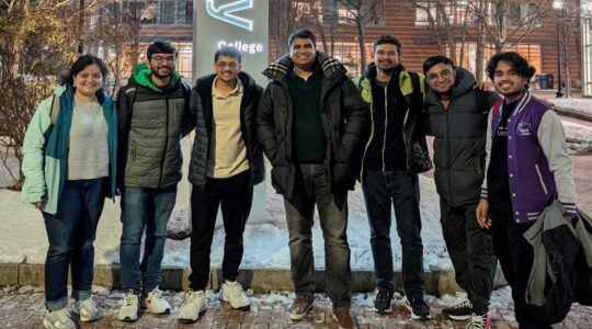 7 members of AWS Cloud Club pose for a photo outdoors at Northeastern's Boston campus with a snowy courtyard in the background