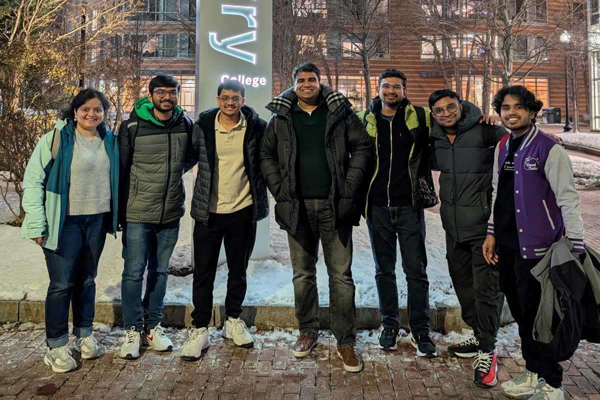 7 members of AWS Cloud Club pose for a photo outdoors at Northeastern's Boston campus with a snowy courtyard in the background