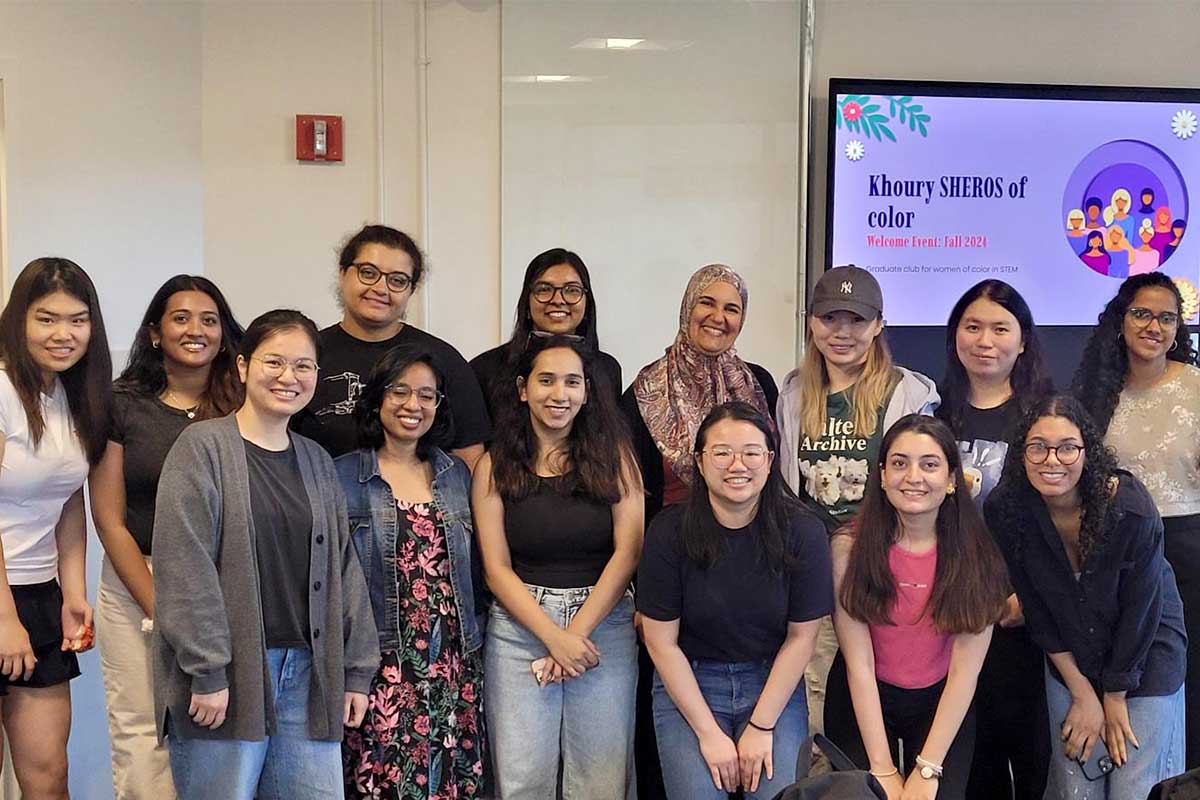 13 members of Khoury SHEROS pose with advisor Ghita Amor-Tijani