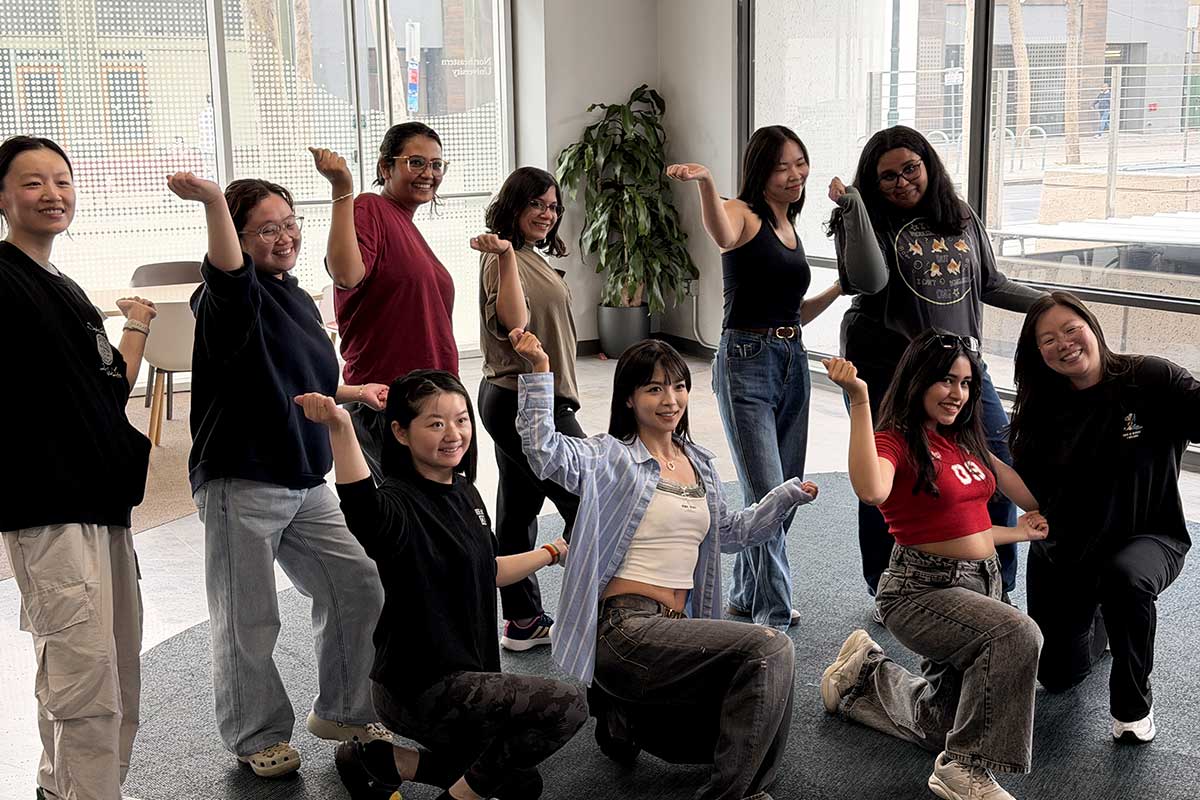 Ten members of HusK Pop practice a dance routine in a studio