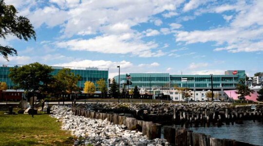 The exterior of the Roux Institute campus building shown with a harbor visible in the foreground