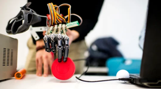 A robotic hand gripping a red disk