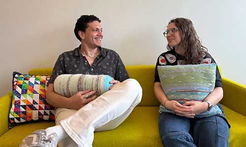 Eduardo Puerta (left) and Sydney Purdue of the Khoury Vis Lab site on a couch holding pillows which use data to create a custom pattern
