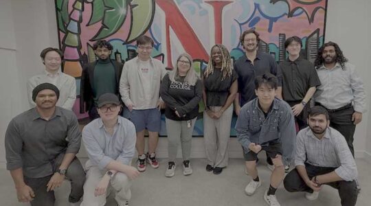 Gabriela Gongora-Svartzman (center) stands with 11 members of the project team in front of a large mural