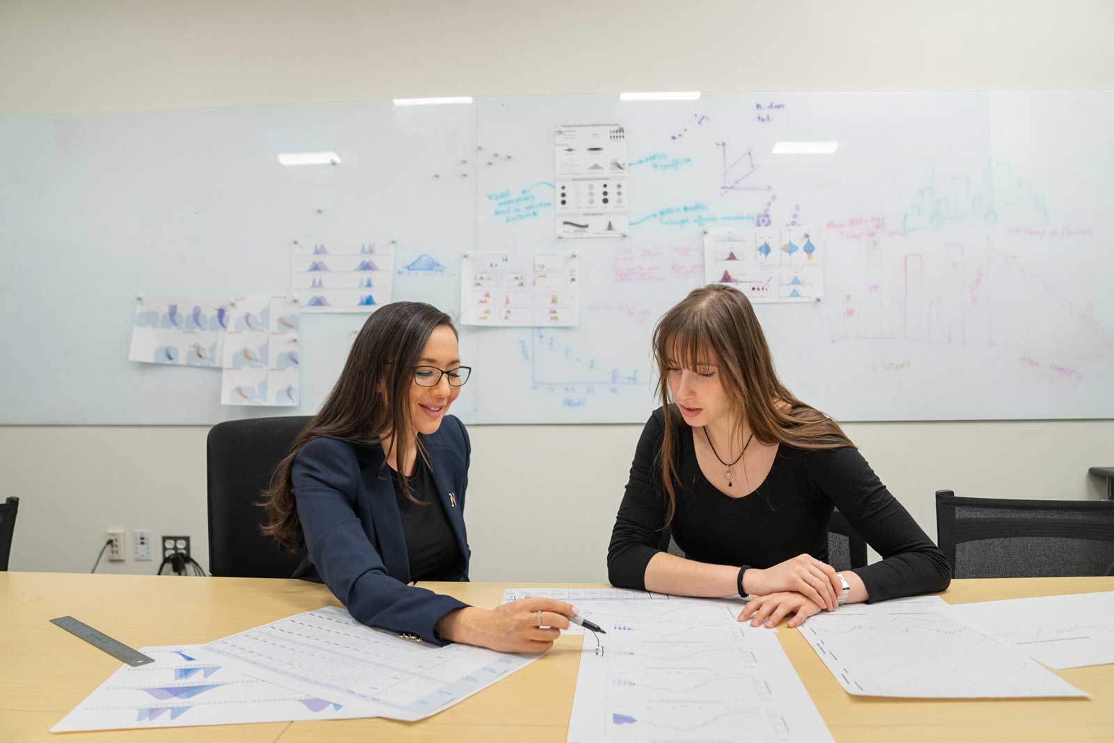 Khoury faculty member Lace Padilla (left) looks at a paper while sittling next to a student