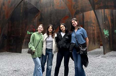 Four students stand in a room in C-mine bezoekersonthaal in Genk, Belgium. The room has rusted metal walls.